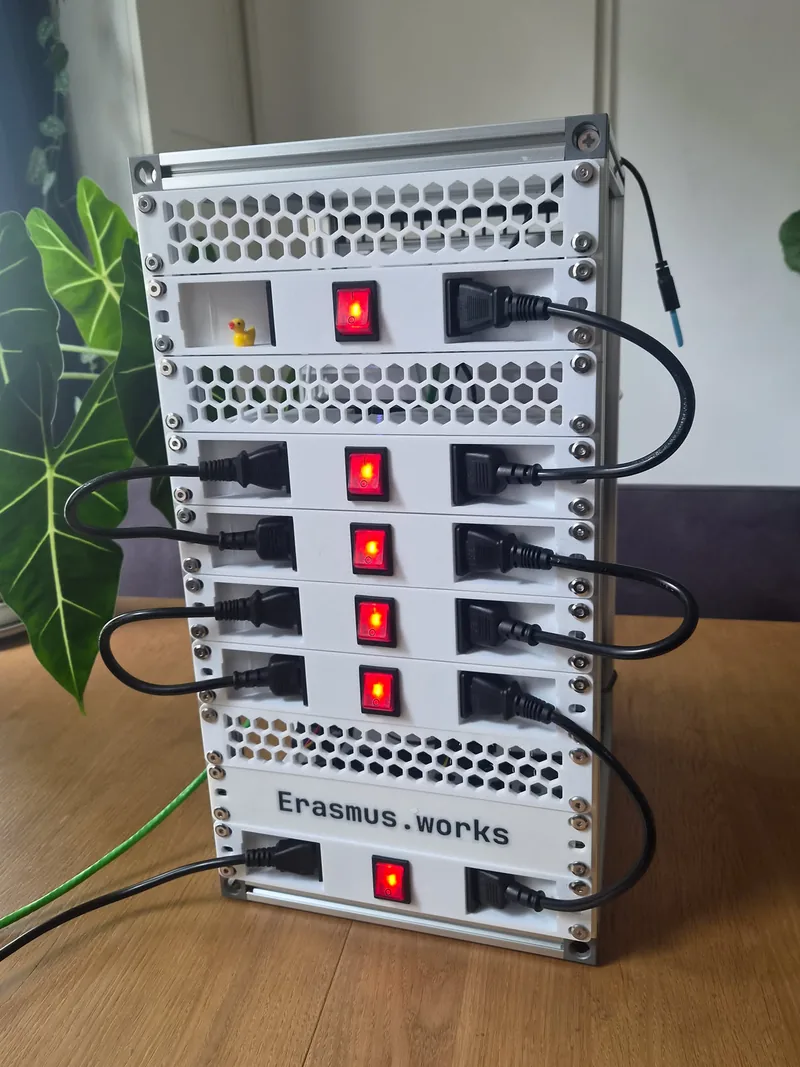 The back of the rack: printed power modules stacked down it, each with a lit red
               rocker switch between an inlet and an outlet, and a short cord looping from one module to the next.